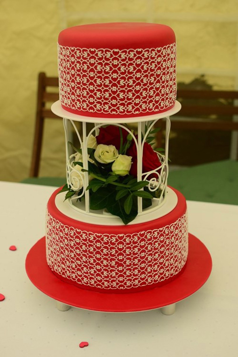 Hochzeitstorte in rot mit weißer Herzchenspitze und echten Blumen